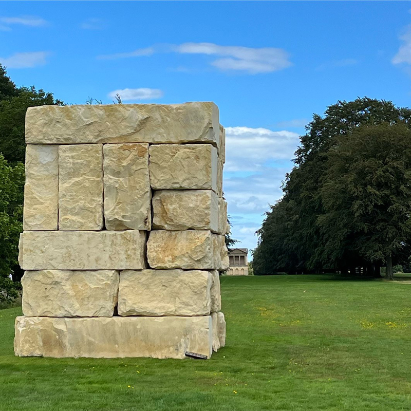 Tower Light Cubed in the foreground with the water tower in the distance across a neat lawn. It looks a bit like a stack of chunky pub chips. Photo: Sarah Simpkin